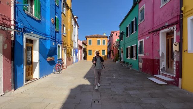 Walking Through Burano: Young Tourist Marvels at Colorful Streets and History in Venice's Picturesque Island. Enjoying the Pastel Buildings, Famous Lace Craft and Rich Culture of Italy