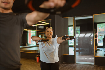 asian woman following weightlifting community class in indoor gym