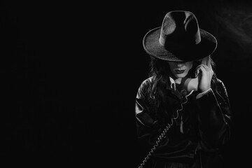 Dark noir portrait of a female detective holding a retro telephone receiver. Private detective, spy, investigation concept. black and white snapshot - obrazy, fototapety, plakaty