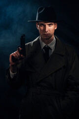 Silhouette of a male detective in a coat and hat with a gun in his hands. A book drama noir...