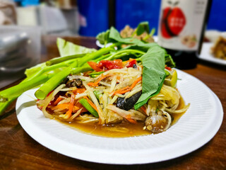 Papaya Salad with salted Crab in white plate on table. Som Tam, Thai green papaya salad with crabs. Thai Food, Isaan Food Dishes, Thai papaya salad.