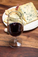 Red porto and cheese pairing, blue matured stilton English cheese served as dessert with walnuts and glass ruby porto wine