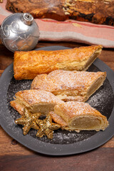 Christmas dessert, fresh baked Dutch filled spicy cookies from puff pastry with almonds on black board close up