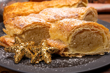 Christmas dessert, fresh baked Dutch filled spicy cookies from puff pastry with almonds on black board close up