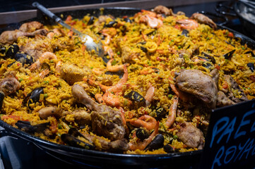 Street food in France, fresh prepared colorful paella with rice and sea food in big pan on street market ready to eat