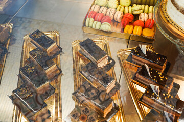 Elegant chocolate cakes with gold flakes on a display shelf.