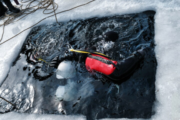 Two divers immersing into an ice hole
