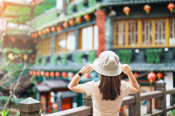 Naklejka premium woman traveler visiting in Taiwan, Tourist with hat sightseeing in Jiufen Old Street village with Tea House background. landmark and popular attractions near Taipei city . Travel and Vacation concept