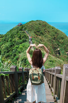 woman traveler visiting in Taiwan, Tourist with backpack sightseeing in Bitou Cape Hiking Trail, New Taipei City. landmark and popular attractions near Taipei. Asia Travel concept