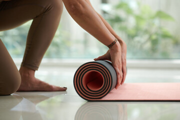 Closeup image of fit young woman rolling out yoga mat, healthy morning routine concept