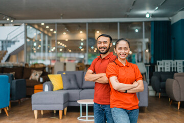 man and woman with crossed hands standing in front of furniture store department - obrazy, fototapety, plakaty
