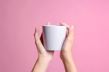 Woman hand holding white blank coffee cup mockup isolated on pink pastel background