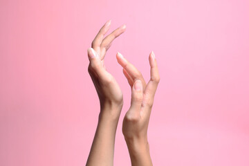 Touching hands of woman on pink pastel background. Femininity, body, skin and beauty.