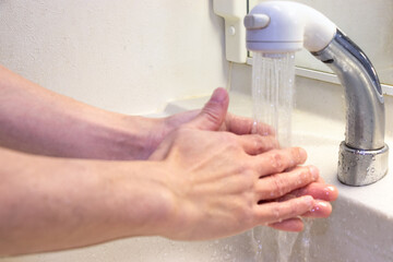 蛇口から流れる水で手を洗う