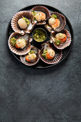 Fried scallops with butter and green sauce served in seashells.