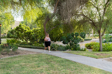 Portrait of a plump woman exercising outdoors doing brisk walking