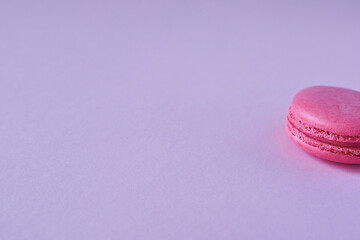 Pink macaroon on a lilac background. Space for text. Half of macaroon.