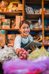 potrait of female asian green grocery seller checking vegetables supplies