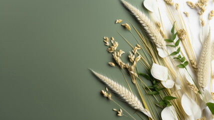 A stylish composition of wheat ears and white flowers arranged on a green background, perfect for designs with a natural theme. - obrazy, fototapety, plakaty