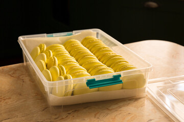 Yellow lids of macaroons in a plastic container