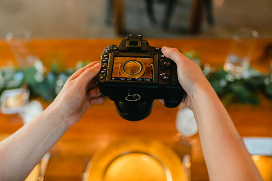 Close up of photographer's hands holding camera taking photo of table