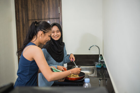 friendship of two multireligious girls cooking preparing breakfast together in the kitchen