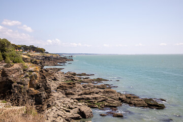 Beach and fishing Brittany rocky coast with fisherman hut on the horizon in Pornic coast
