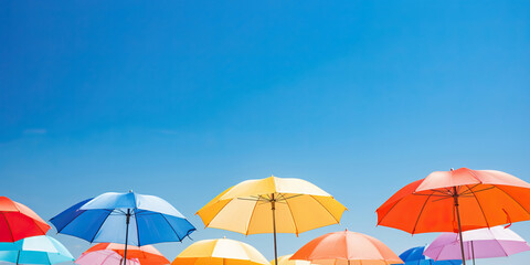 Fototapeta na wymiar Abstract summer background with colorful umbrellas against blue sky