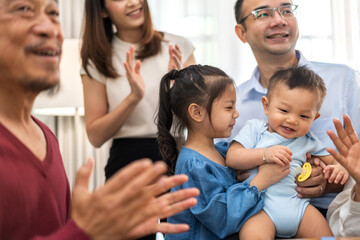 Portrait of happy love asian grandfather with grandmother playing with asian baby and little cute girl on bed.Big family love with their laughing grandparents smiling together.Family and togetherness