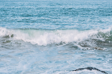 Wave splashes close-up. Crystal clear sea water hitting rock formations in the ocean in San Francisco Bay, blue water, pastel colors.