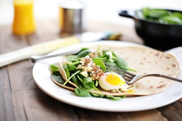 breakfast flaxseed wrap with eggs and spinach on a skillet