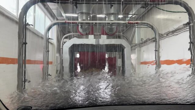 Washing a car in a car wash. Water on glass.