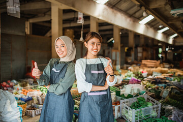 two female vegetable seller standing with thumb up gesture