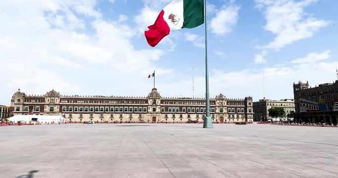 slow motion shot of mexican flag flying on the zocalo in front of national palace in mexico city