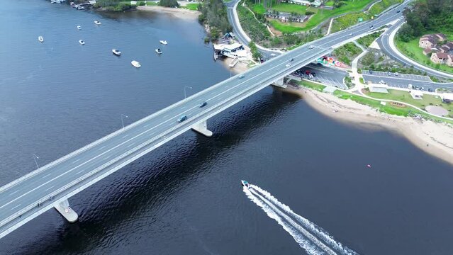 Drone aerial cars traffic passing over highway with boat on river transport infrastructure Clyde River Batemans Bay South Coast Australia