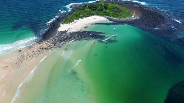 Drone aerial people kitesurfing sandbar off remote ocean beach with reef waves Island Bendalong Manyana South Coast Australia 4K