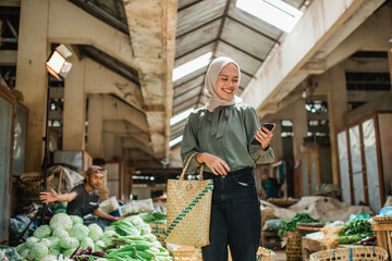 female customer holding phone and standing at farmer market