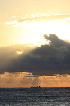 commercial cargo ship sailing in the sun and dark clouds