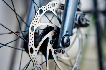 Part of the bicycle's braking system. Grey metal brake disc and brake pads on road bike, close up. - Powered by Adobe