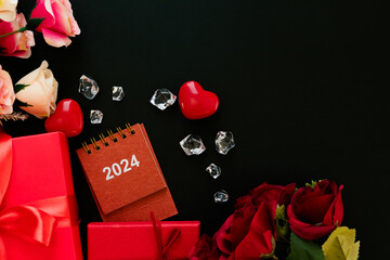 Valentine's Day decorations concept. Top view photo of gift boxes with rose and heart on black background with copyspace