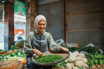 asian seller sitting and checking her vegetable products at her stall