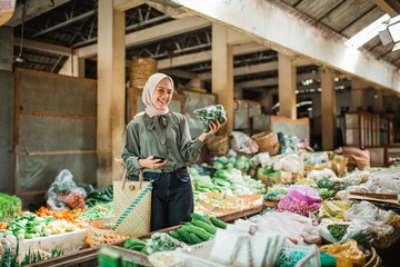 female customer holding vegetables at greengrocery stall in farmer market