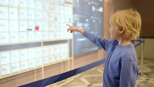 A child of primary school age visiting a science museum. The boy is exploring a table of chemical elements. Curious and smart child. Going to a museum as a family is quality time with your kids.