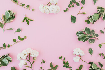 White flowers with green leaves on pink background. Flat lay, Top view. Floral frame