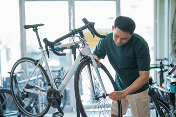 Fototapeta na wymiar asian male employee assembles a new bike while working at a bike shop