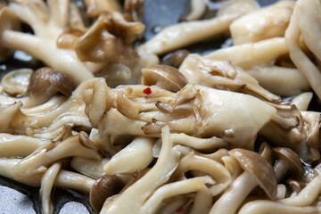 きのこ(ブナシメジと舞茸)をフライパンで炒める調理シーン。
