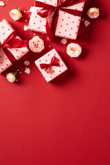 Valentines day vertical background with gift boxes and rose buds on red table. Top view. Flat lay.