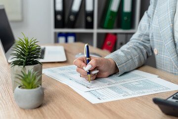 Business woman filling  individual income tax return form, tax documents in office