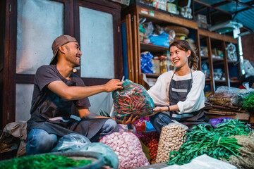 happy female seller receiving wrapped vegetables from male seller at vetetable stall