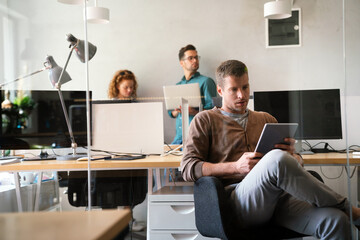 Portrait of young businessman working on digital tablet in office. Business designer startup concept